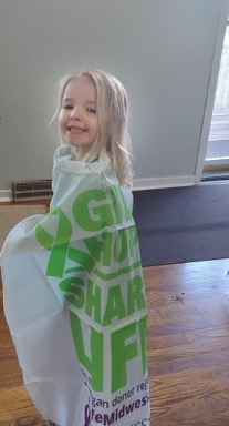 Photo of a little girl wearing a Give Hope Share Life cape.