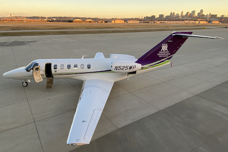 Sunset photo of the MTN airplane at the KC downtown airport with the skyline behind it.