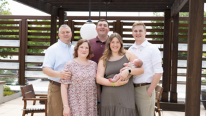 A portrait style photo of Drew Hedrick's family including dad, brother, brother-in-law, mom, sister and nephew.