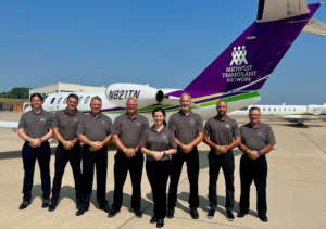 Pilots standing in formation in front of a plane owned by Midwest Transplant Network.