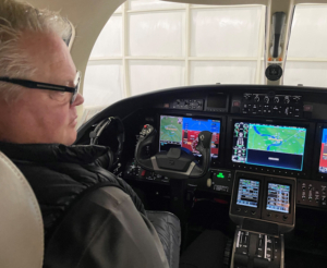 A pilot sits at the controls of a small plane.