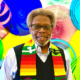 Rev. Isaac Ruffin, an African American male, wearing a colorful scarf representing Black heritage, standing in front of an art display of glass plates in various shades of primary colors.