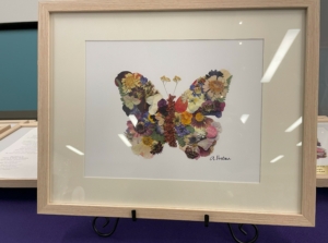A butterfly made of pressed flowers in a photo frame.