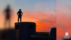 Drew standing on a trailer looking into the sunset. 