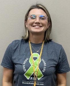 A woman wearing glasses, smiling for the camera.